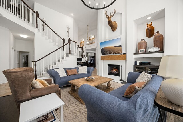 living room with a towering ceiling, built in features, and a notable chandelier