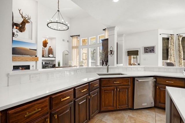 kitchen with dark brown cabinets, sink, pendant lighting, light tile patterned floors, and a chandelier