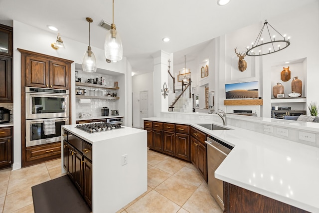 kitchen featuring backsplash, stainless steel appliances, sink, a chandelier, and a center island