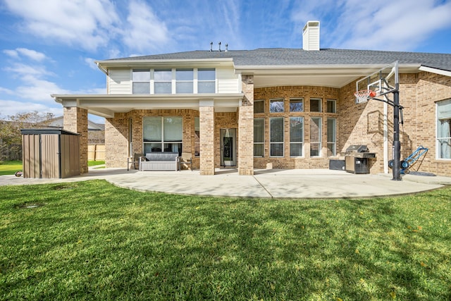 rear view of house featuring a lawn, a storage unit, and a patio