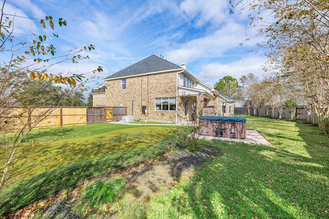 rear view of property featuring a lawn and a hot tub