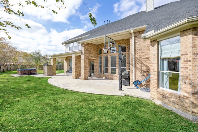 back of property with a yard, a patio, and a hot tub