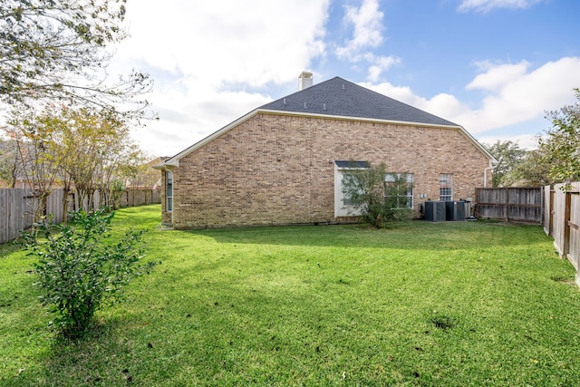 rear view of property with a yard and central AC unit