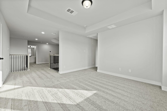 unfurnished room with light colored carpet and a raised ceiling