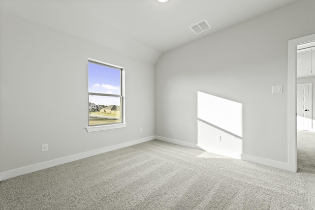 carpeted empty room featuring vaulted ceiling