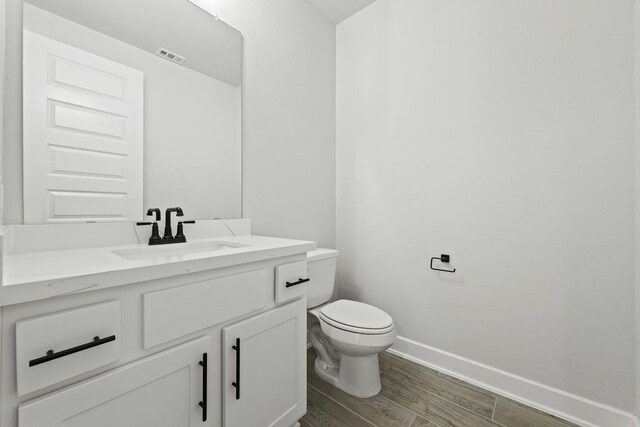 bathroom with hardwood / wood-style floors, vanity, and toilet