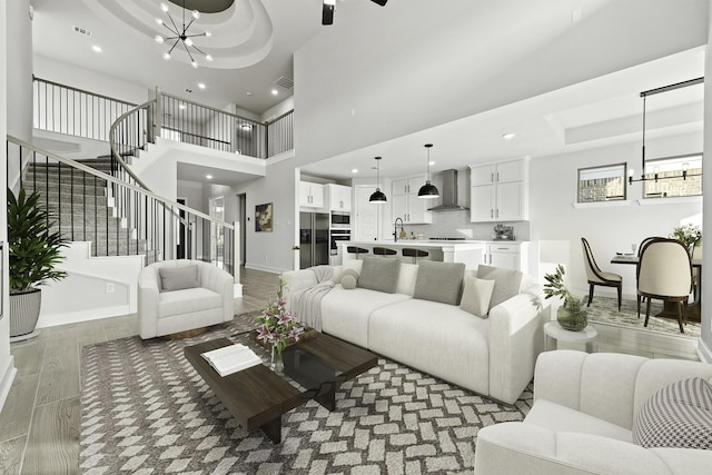 living room featuring sink, hardwood / wood-style floors, a high ceiling, and a notable chandelier