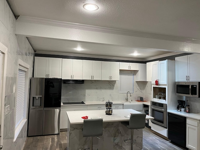 kitchen with black appliances, a kitchen island, white cabinetry, and sink