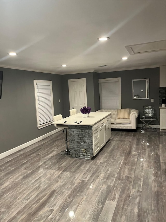 kitchen with a kitchen breakfast bar, crown molding, dark wood-type flooring, white cabinets, and a center island