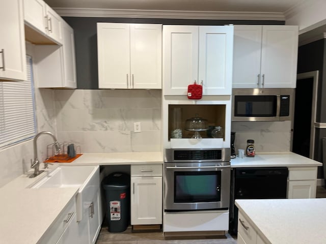 kitchen featuring white cabinetry, ornamental molding, appliances with stainless steel finishes, and tasteful backsplash