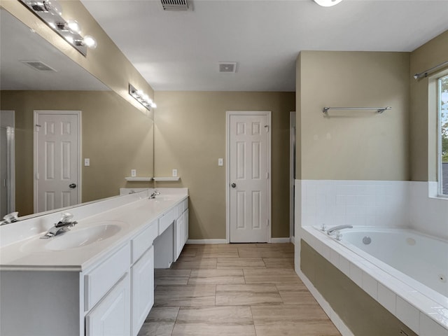 bathroom featuring vanity and tiled tub