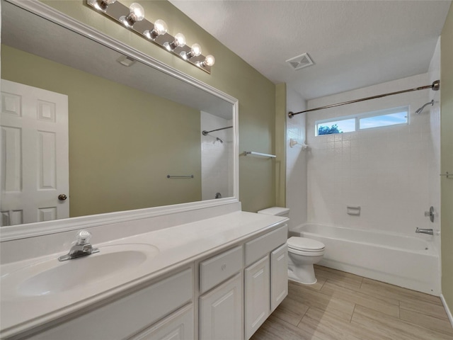 full bathroom featuring a textured ceiling, vanity, toilet, and tiled shower / bath