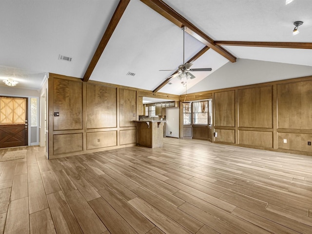 unfurnished living room with light wood-type flooring, lofted ceiling with beams, ceiling fan, and a healthy amount of sunlight