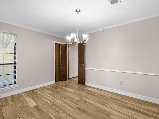 empty room with light hardwood / wood-style floors, an inviting chandelier, and crown molding