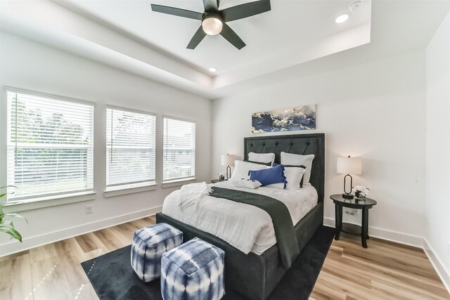 bedroom with a tray ceiling, ceiling fan, and hardwood / wood-style floors