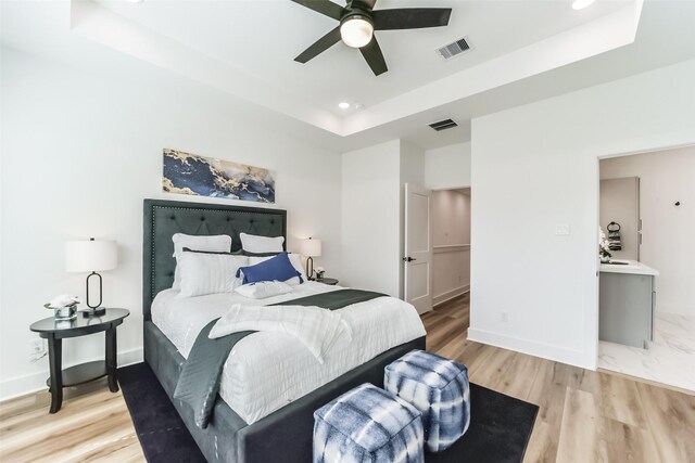 bedroom with a raised ceiling, ceiling fan, and hardwood / wood-style floors