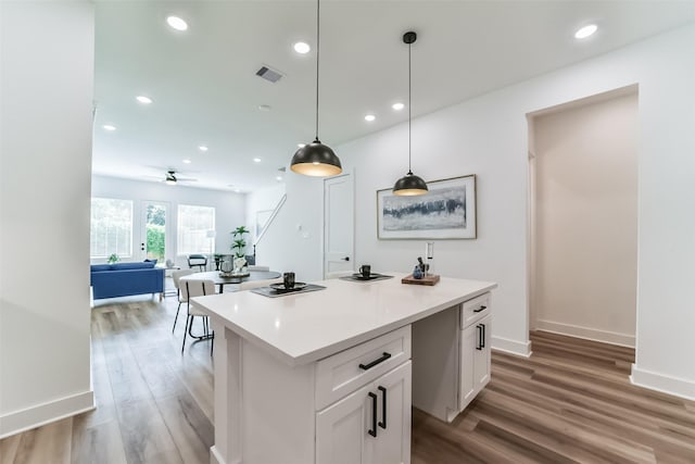 kitchen with hardwood / wood-style floors, a kitchen island, decorative light fixtures, ceiling fan, and white cabinets