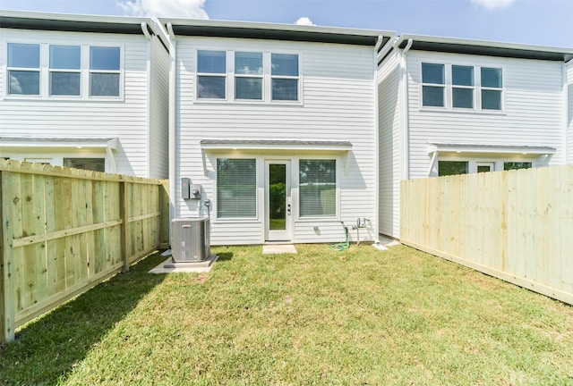 rear view of house featuring central air condition unit and a yard