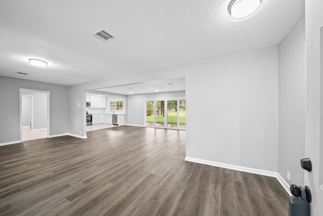 unfurnished living room with a textured ceiling and dark hardwood / wood-style floors