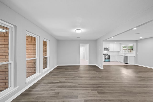 unfurnished living room featuring a textured ceiling, dark wood-type flooring, and sink