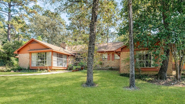 ranch-style house featuring a sunroom and a front lawn