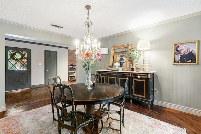 dining space with dark wood-type flooring, ornamental molding, and a textured ceiling