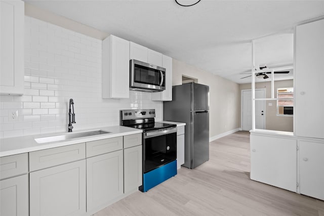 kitchen featuring white cabinetry, sink, stainless steel appliances, backsplash, and light hardwood / wood-style floors