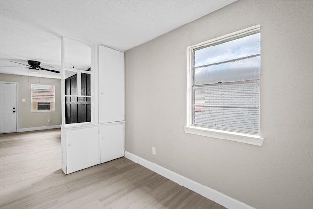 spare room with ceiling fan, light hardwood / wood-style floors, a textured ceiling, and a wealth of natural light