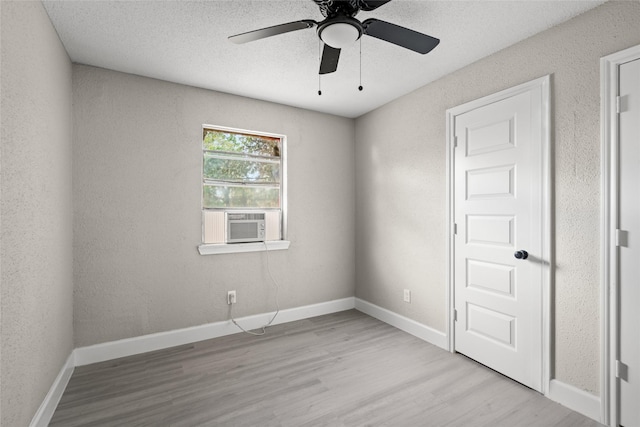 spare room featuring a textured ceiling, light hardwood / wood-style flooring, cooling unit, and ceiling fan