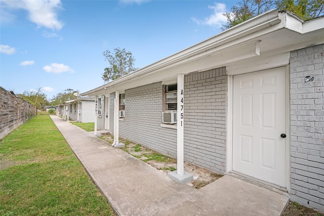 doorway to property featuring a yard and cooling unit