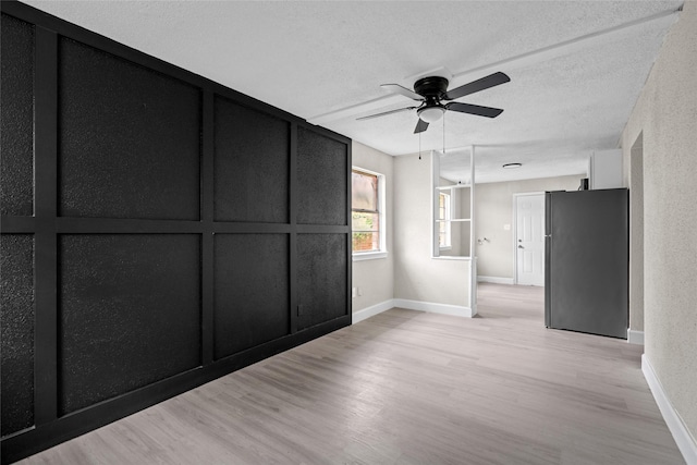 spare room with ceiling fan, light hardwood / wood-style floors, and a textured ceiling