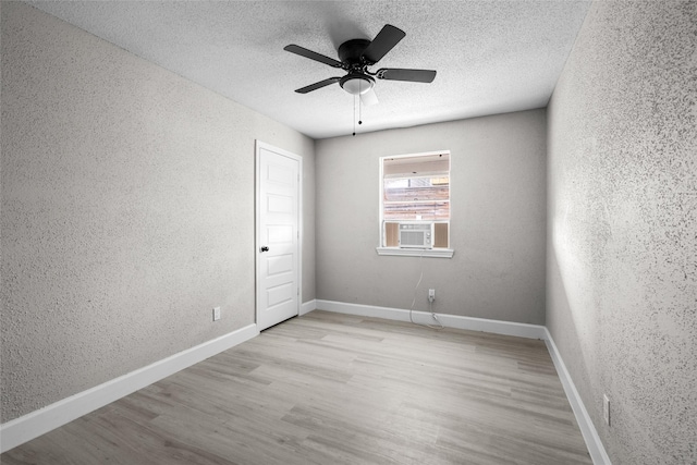 unfurnished room featuring ceiling fan, cooling unit, light hardwood / wood-style floors, and a textured ceiling