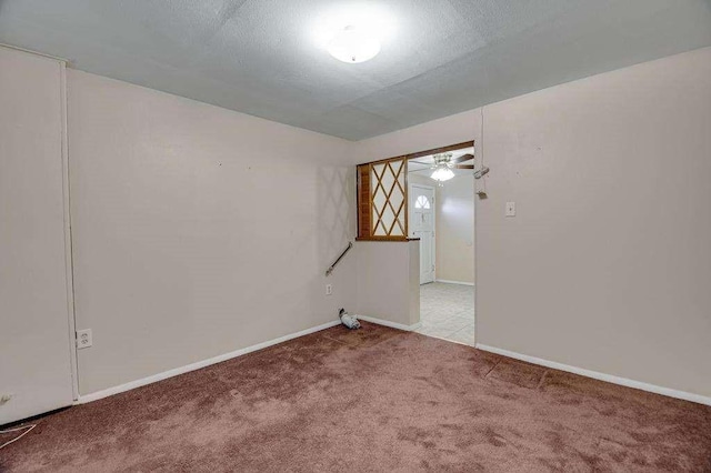 empty room featuring ceiling fan, light colored carpet, and a textured ceiling