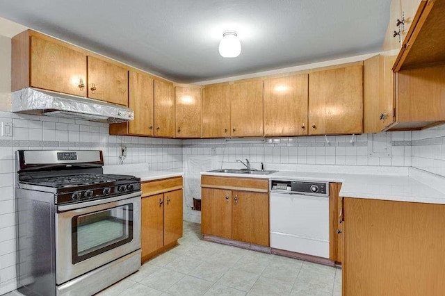 kitchen with gas range, backsplash, white dishwasher, and sink