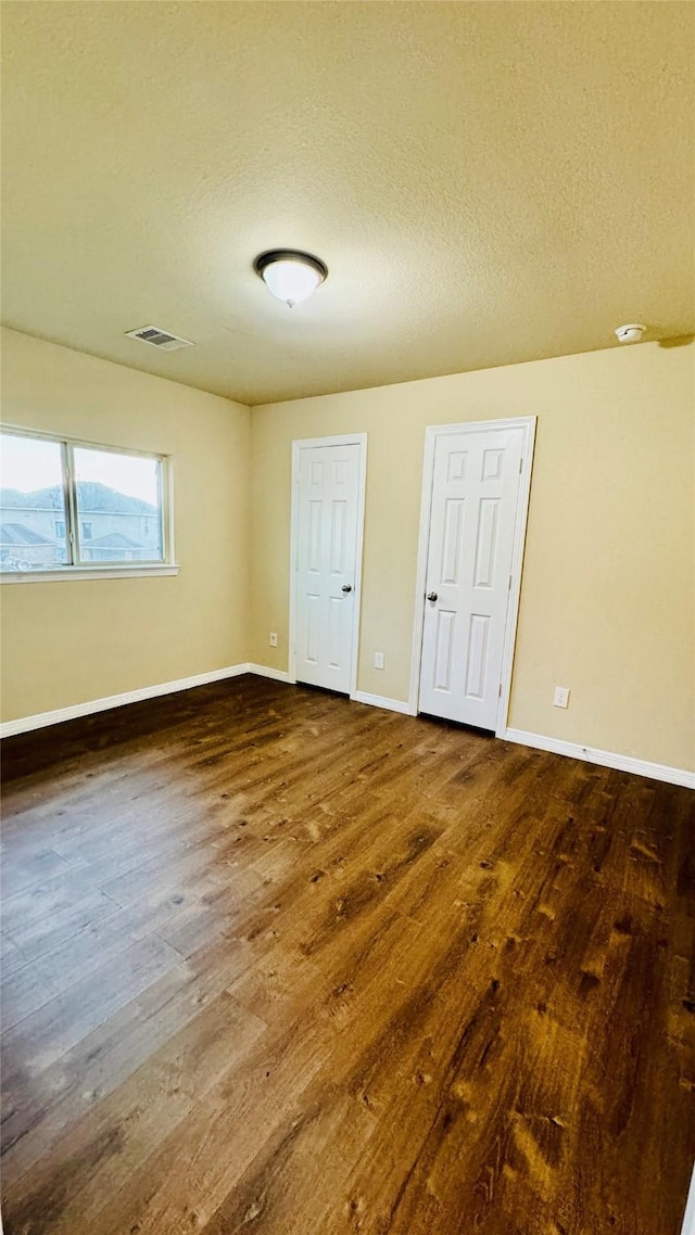 unfurnished bedroom with a textured ceiling and dark wood-type flooring