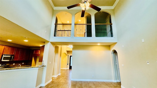 kitchen with ceiling fan, ornamental molding, a towering ceiling, and range