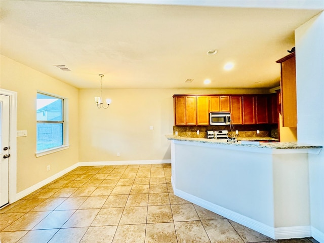 kitchen with light stone counters, stainless steel appliances, an inviting chandelier, hanging light fixtures, and light tile patterned flooring