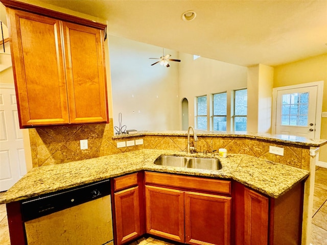 kitchen with kitchen peninsula, light stone counters, stainless steel dishwasher, ceiling fan, and sink