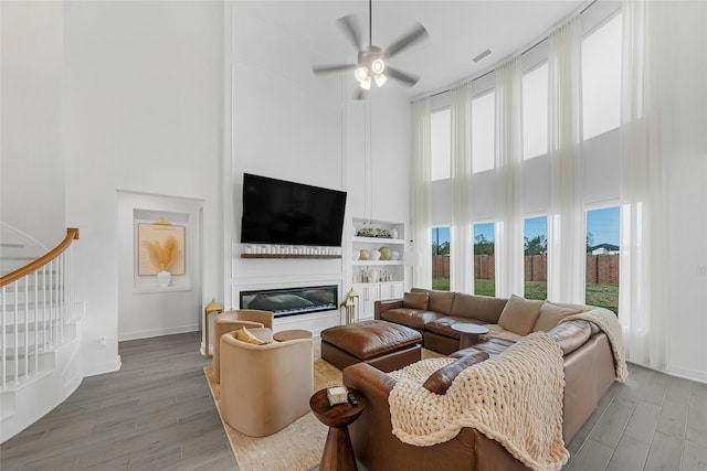 living room featuring hardwood / wood-style floors, ceiling fan, and a high ceiling