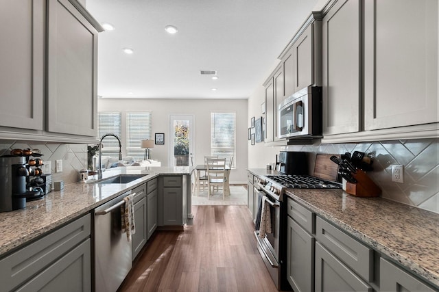 kitchen with light stone countertops, sink, dark hardwood / wood-style floors, and appliances with stainless steel finishes