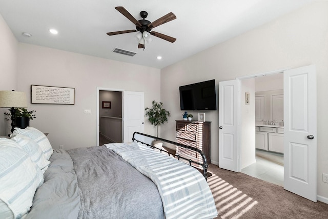 carpeted bedroom featuring ceiling fan and ensuite bath