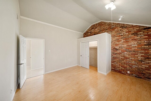 interior space featuring brick wall, lofted ceiling, and light wood-type flooring