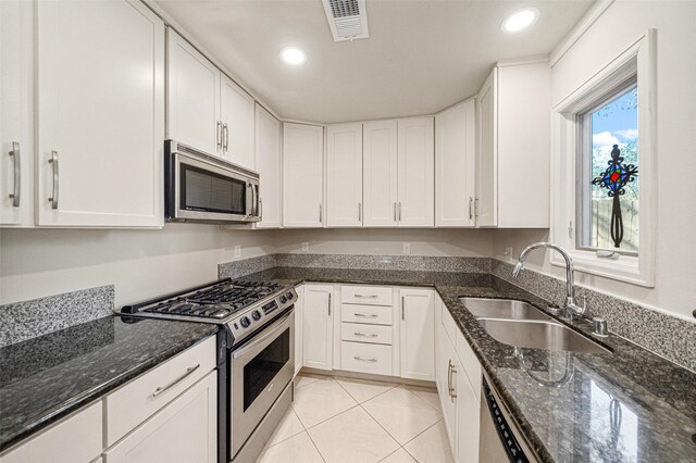 kitchen with dark stone countertops, sink, white cabinetry, and stainless steel appliances