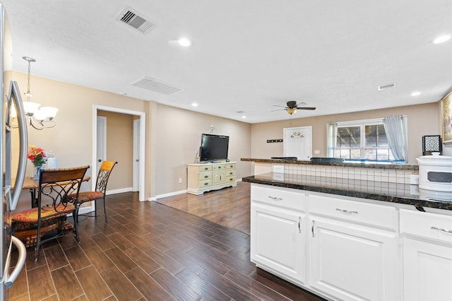 kitchen featuring decorative backsplash, ceiling fan with notable chandelier, decorative light fixtures, white cabinets, and dark hardwood / wood-style floors