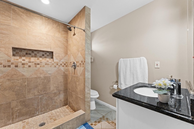 bathroom featuring a tile shower, vanity, and toilet