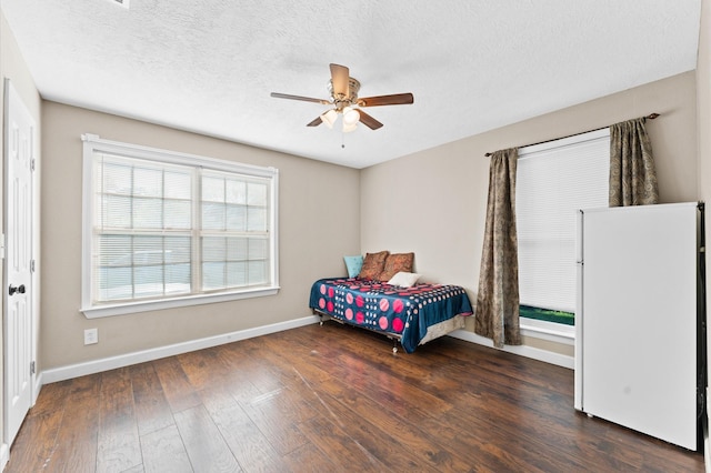 bedroom featuring ceiling fan, dark hardwood / wood-style flooring, a textured ceiling, and white refrigerator