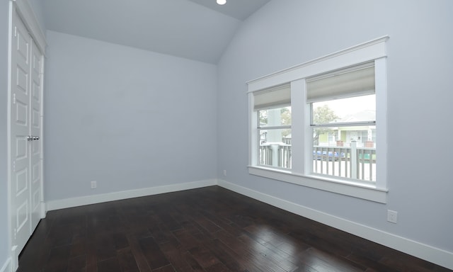 empty room with dark wood-type flooring and vaulted ceiling