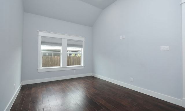 spare room with dark hardwood / wood-style floors and vaulted ceiling