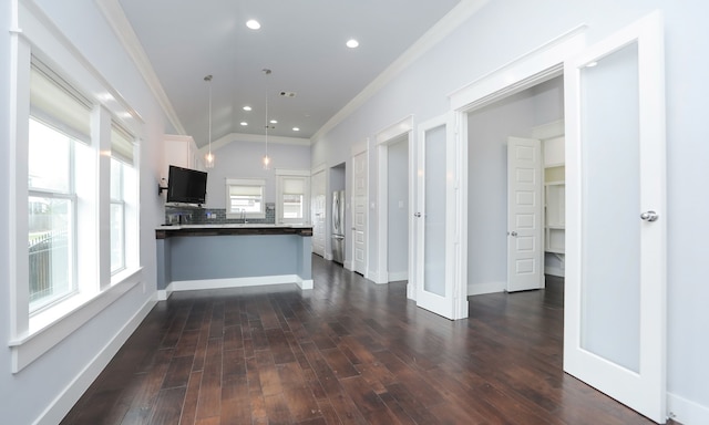 kitchen featuring kitchen peninsula, dark wood-type flooring, crown molding, white cabinets, and hanging light fixtures