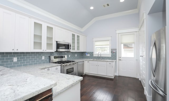 kitchen featuring sink, vaulted ceiling, light stone countertops, white cabinetry, and stainless steel appliances